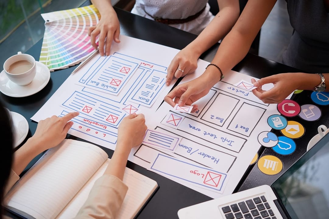 Team ordnet Papier-Wireframes und Farbmuster bei einem Workshop – Onectus-Vergleich von Service Design und Design Thinking