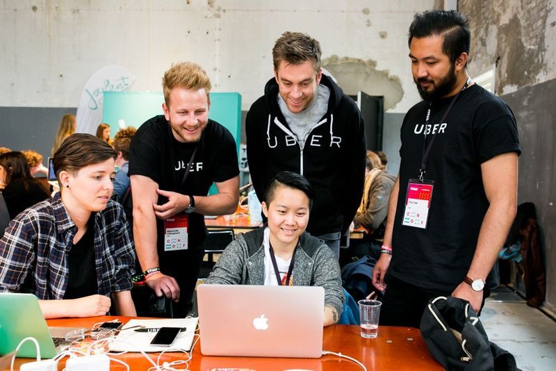 Ingenieure besprechen einen Laptop auf einer Technologieveranstaltung – Onectus-Analyse von Uber Engineering und zuverlässigen Plattformen