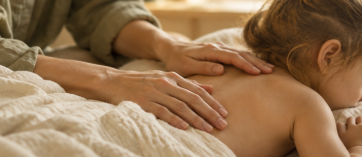 A practitioner's hands resting very lightly on a child's back