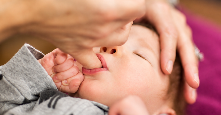 A practitioner's hands resting lightly on a child's back