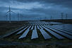 Solar panels and wind turbines with transmission towers at dusk