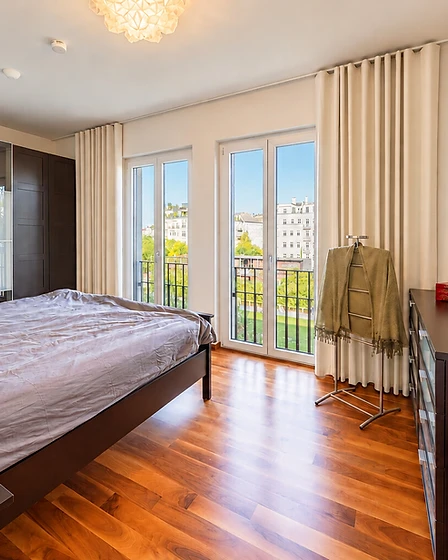 Schlafzimmer mit Walnuss-Parkett und bodentiefen Balkontüren