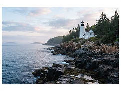 A white lighthouse on granite rocks along the Maine coast