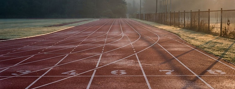 An empty running track with white lane lines at sunrise
