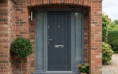 A grey composite front door on a brick house