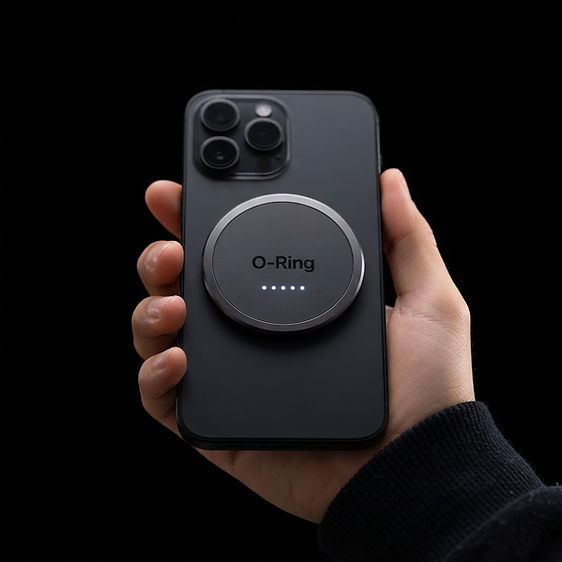 O-Ring magnetic accessory attached to the back of a black smartphone in hand