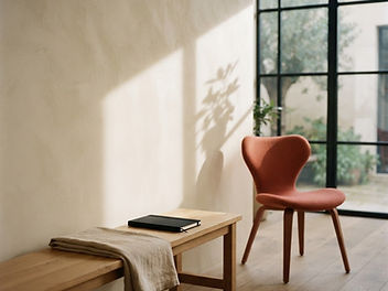 Quiet studio interior with warm plaster walls and a single coral chair