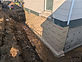 Foundation wall wrapped in waterproofing membrane beside excavation