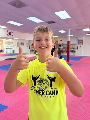 A camper giving two thumbs up in a bright neon camp shirt