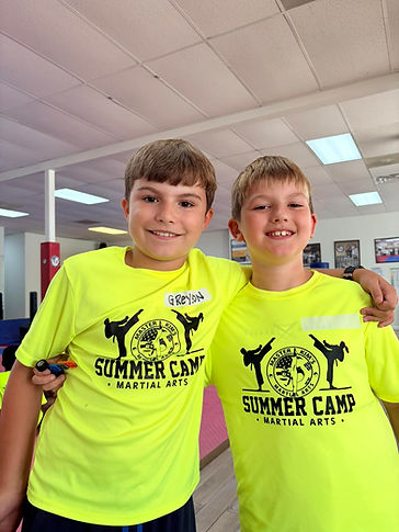 Two smiling campers with their arms around each other in Master Kim's Summer Camp shirts