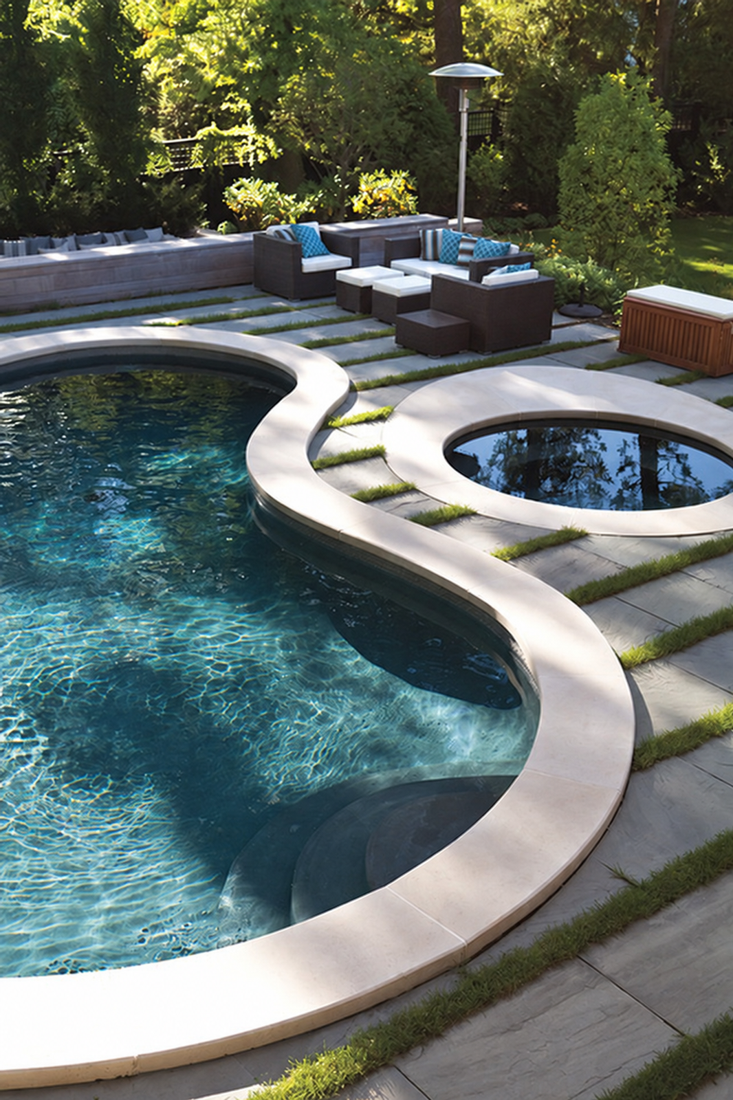 Curved swimming pool with circular spa framed by linear bluestone paving and grass bands at Playful Music
