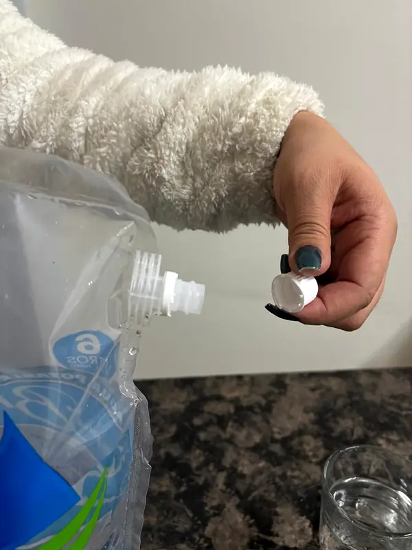 Persona abriendo la tapa válvula de una bolsa de agua de 6 litros