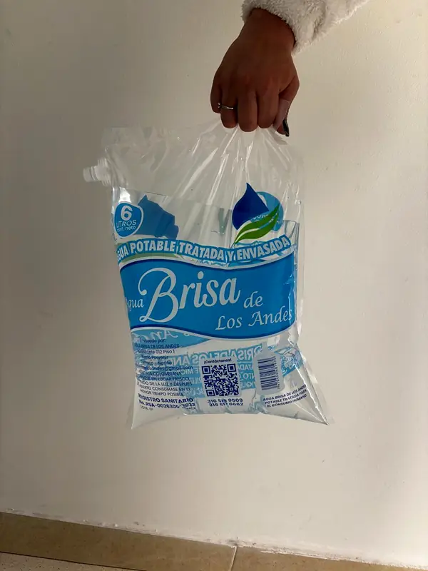 Persona llevando una bolsa de agua de 6 litros por el asa