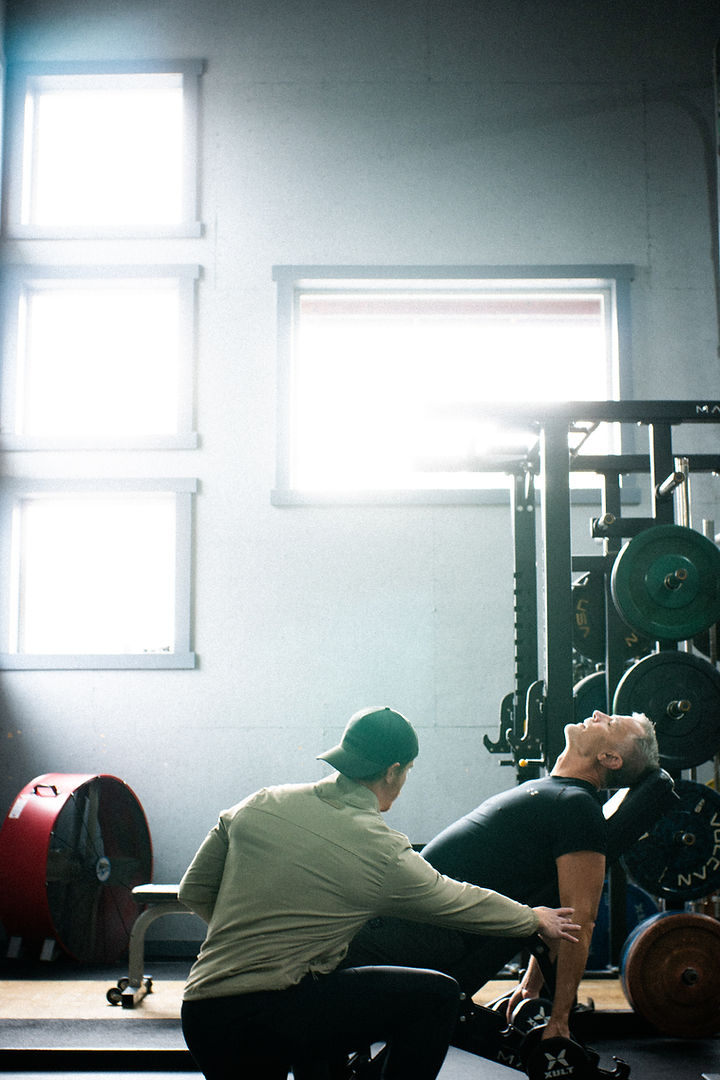 Trainer coaching a member through an incline dumbbell press