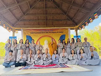 Chư Tăng và Phật tử dưới mái che gỗ, phía sau là băng rôn Tu Viện Bồ Đề Tâm