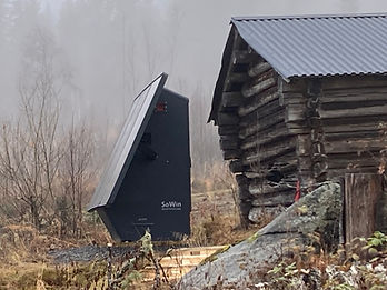 SoWin Kraftstasjon installert utendørs i tåkete skoglandskap ved en gammel tømmerhytte