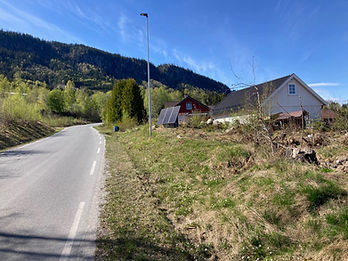 SoWin kraftstasjon på en gressmark ved en svingende vei med rødt og hvitt hus i bakgrunnen