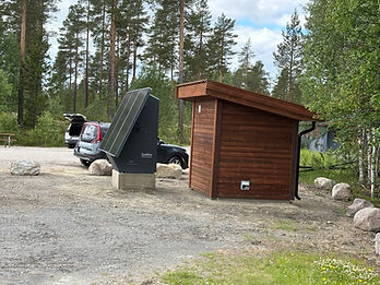 SoWin kraftstasjon installert ved siden av en trehytte i skogterreng med grus og stein