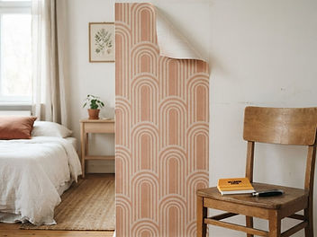 Terracotta and cream arch pattern peel and stick wallpaper peeled back at the top corner to show the clean painted wall beneath, next to a wooden chair with a smoothing tool and craft knife