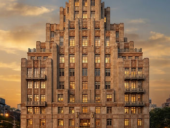 1920s Art Deco apartment building with stepped setbacks, vertical lines and geometric stone ornament in golden evening light