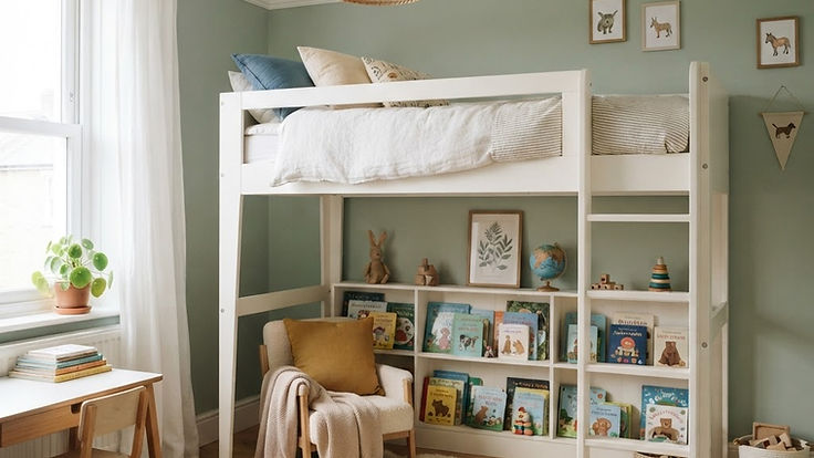 White painted wooden loft bed in a child's bedroom with a cosy reading nook and bookshelves underneath, soft sage walls, a rattan pendant and natural daylight