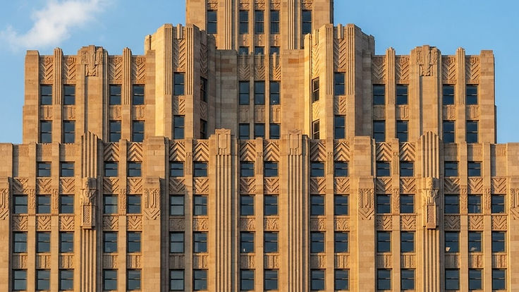 Art Deco building facade with stepped geometric details and strong vertical lines in warm sunlight
