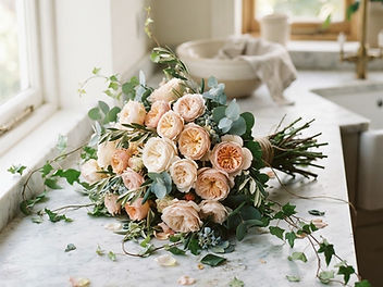 Hand-tied bouquet of garden roses surrounded by eucalyptus, olive and trailing ivy on a marble kitchen counter