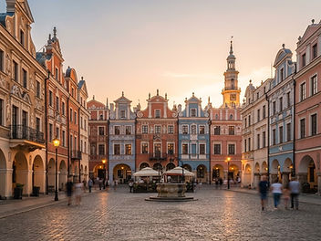 Colourful Polish old town market square at sunset with Renaissance and Baroque townhouses, arcades, a cobbled square, a fountain and a tall town hall tower