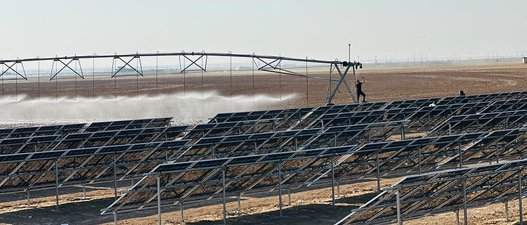 Ground-mounted solar panels beside agricultural irrigation equipment.