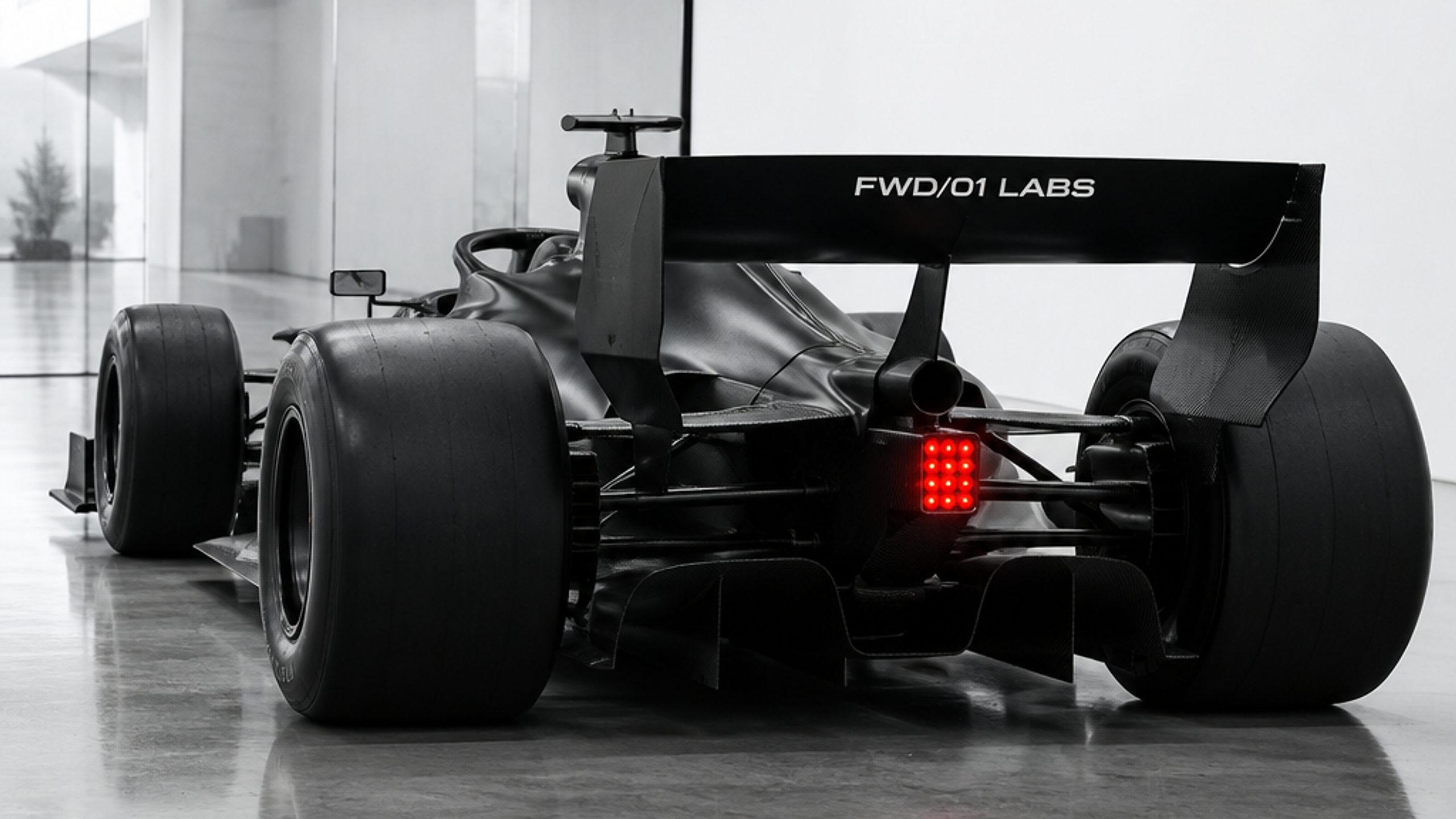 Rear three-quarter view of a black Formula-style FWD/01 Labs race car in a white garage