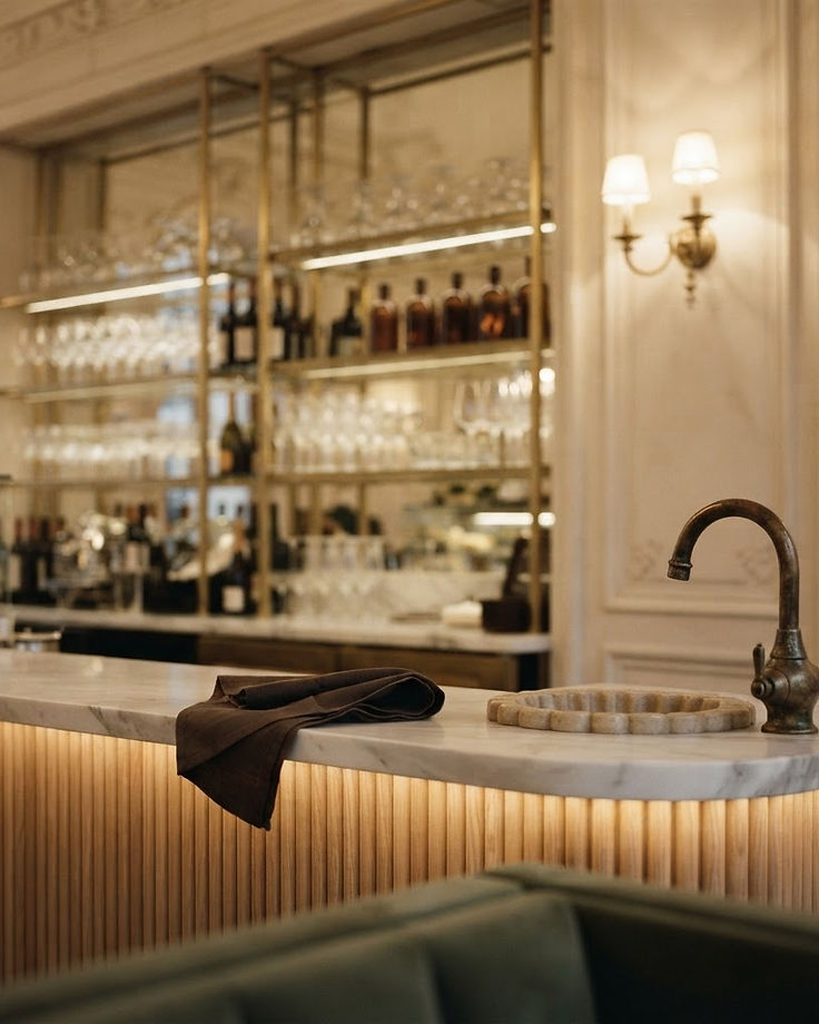 Antique bronze fittings above a fluted stone basin in warm light