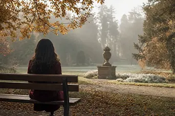Femeie singură pe o bancă în Grădina Botanică din București, într-o dimineață cu ceață.