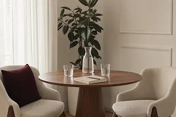 Cameră de consultație minimalistă, cu două scaune, o masă rotundă, apă și un caiet.