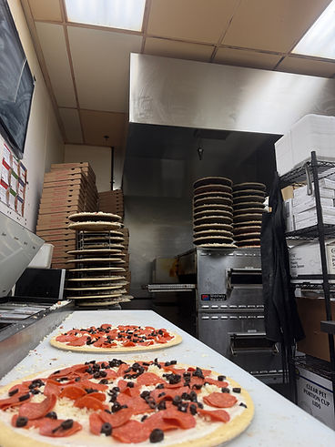 Fresh pizzas prepped on the counter by the oven