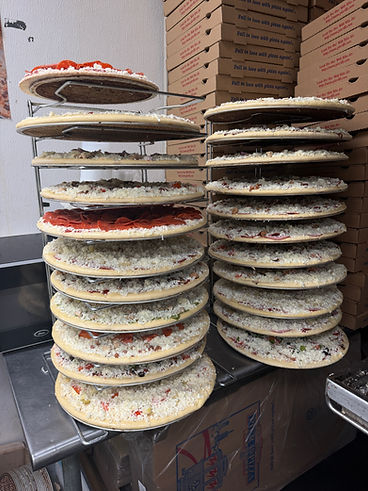 Racks of topped pizzas ready for the oven
