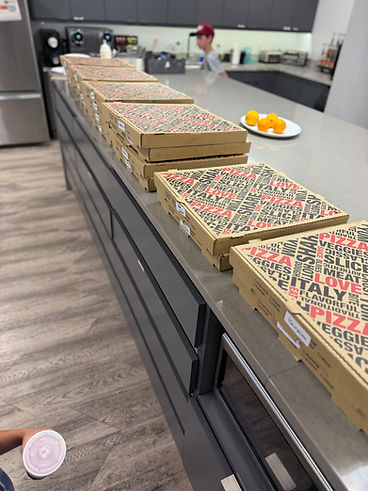 Pizza boxes lined up on a kitchen counter for an event