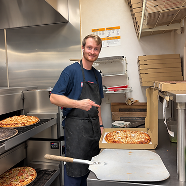 Aidan boxing up a fresh pizza by the oven