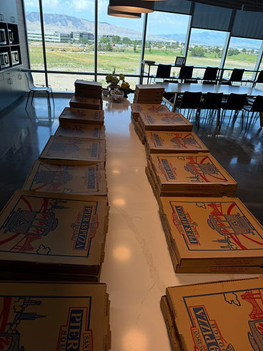 Pizza boxes lined up on a long table by the window
