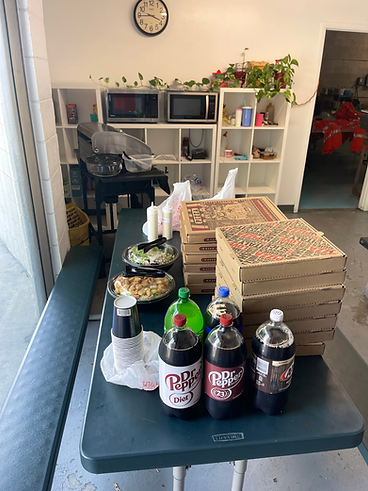 Lunch spread with pizza boxes, drinks, and sides