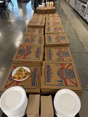 Pizza boxes lined up with plates and napkins at an event