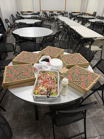 Catering spread with pizza boxes and salad tray set up in a conference room
