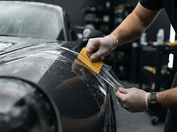 Installing clear paint protection film on a car fender with a squeegee