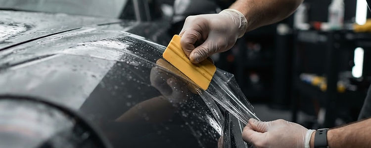 Installing clear paint protection film on a car fender with a squeegee