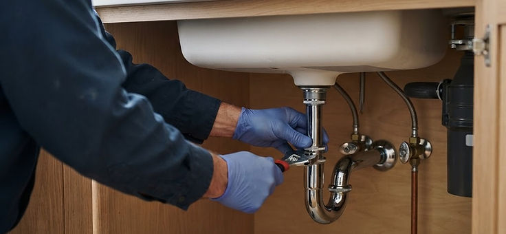 Drain trap and water supply connections beneath a kitchen sink