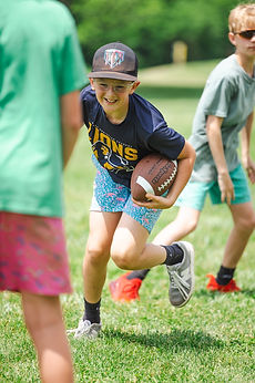 A GCA Lions student running with a football