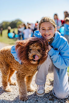 A smiling GCA student hugging a dog in a lion mane