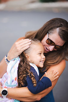 A mom hugging her smiling daughter at drop-off