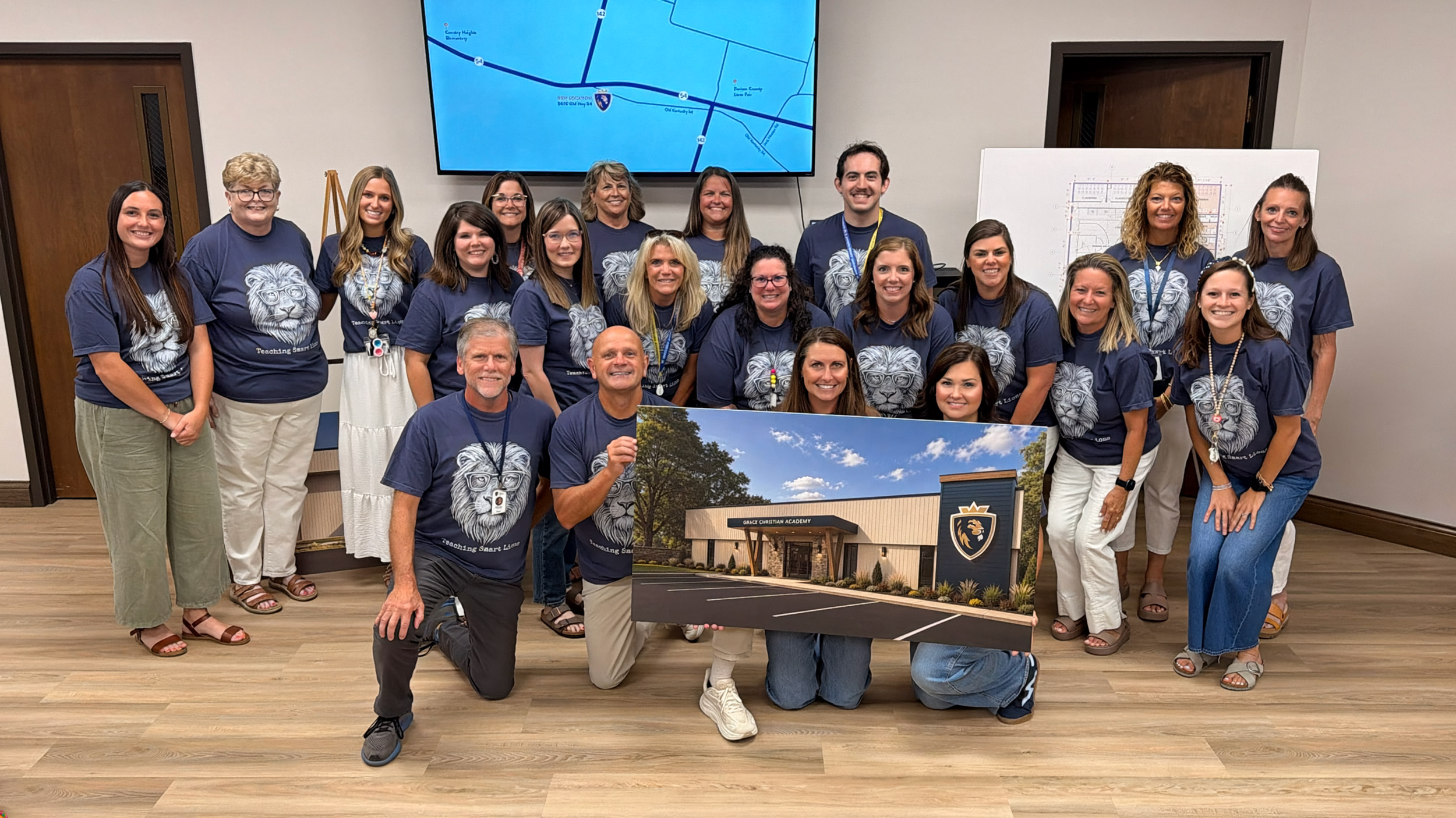 GCA faculty and staff together, holding a rendering of the new campus