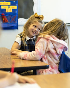 Two young GCA students smiling together in class