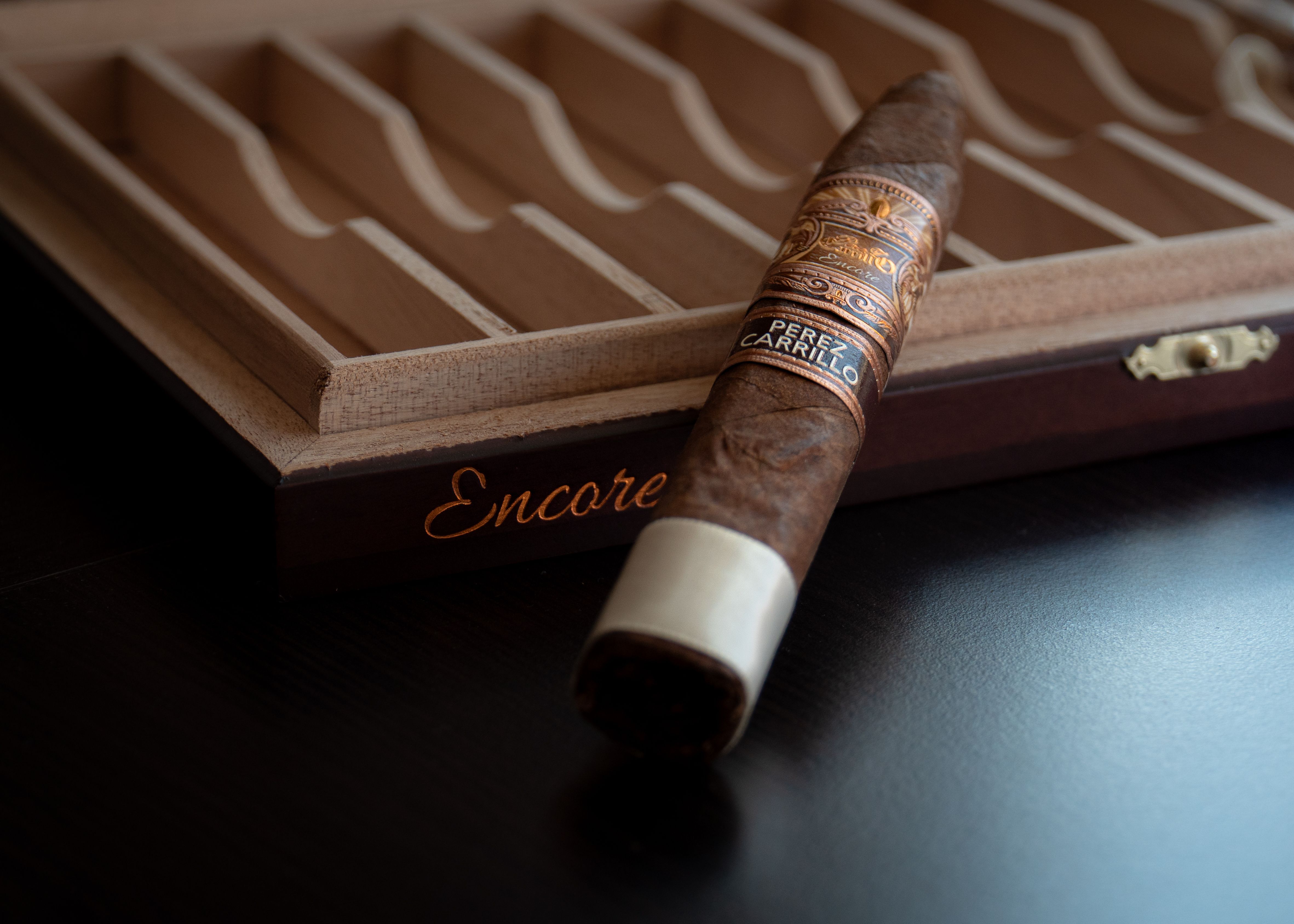 A Perez Carrillo Encore cigar laid across an open cigar box with velvet dividers